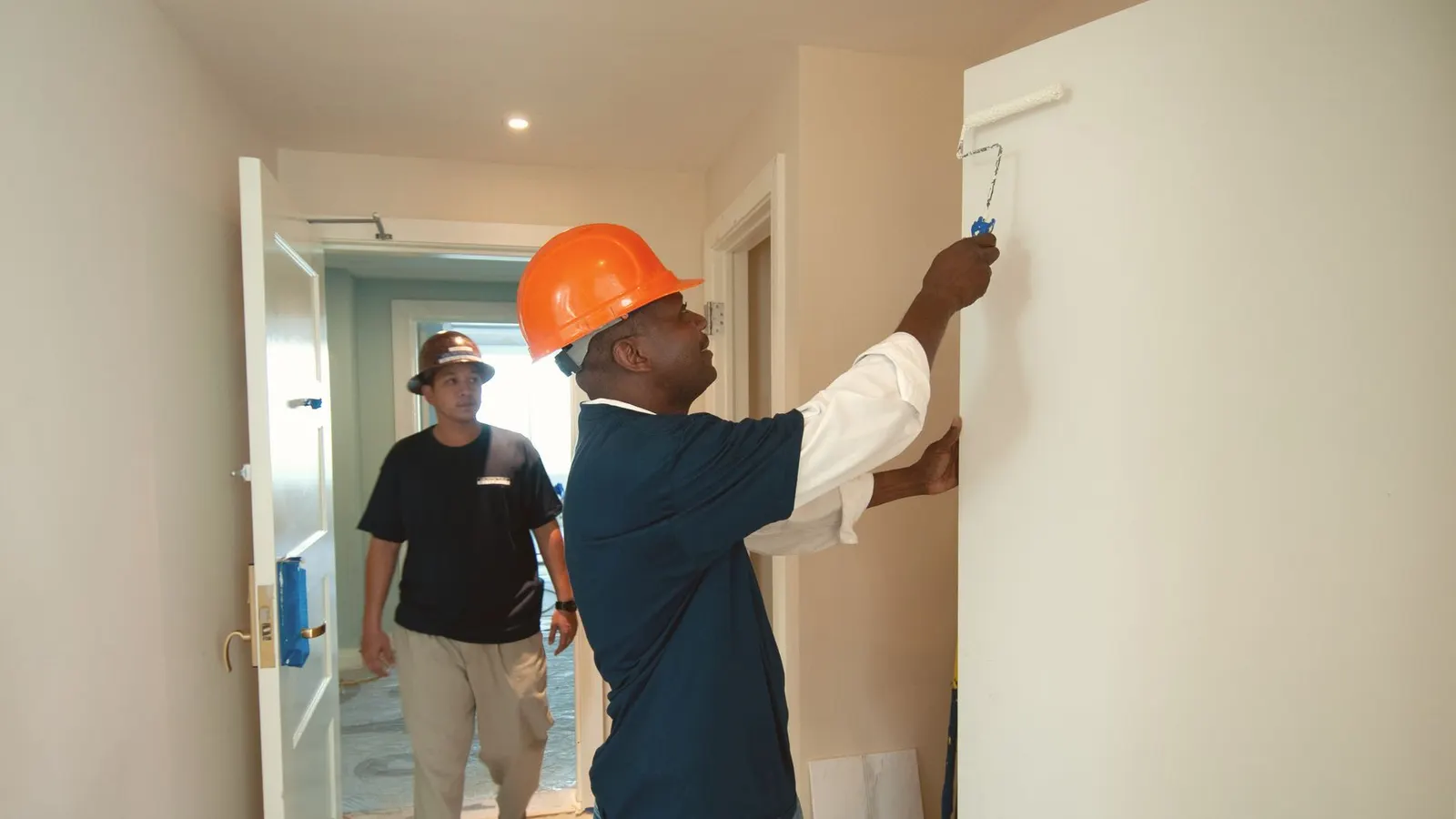 Interior painting in Lynn, MA, a painter rolling paint on a hallway wall